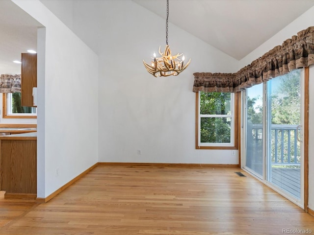 unfurnished dining area featuring vaulted ceiling, an inviting chandelier, and light hardwood / wood-style floors