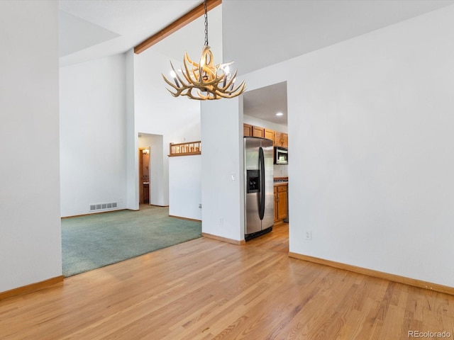 unfurnished dining area featuring a chandelier, light colored carpet, and vaulted ceiling with beams