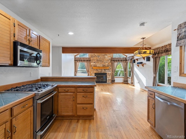 kitchen featuring tile counters, plenty of natural light, and stainless steel appliances