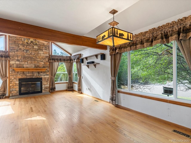 unfurnished living room with light wood-type flooring, a fireplace, and vaulted ceiling with beams