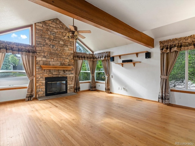 unfurnished living room with lofted ceiling with beams, light hardwood / wood-style flooring, ceiling fan, and a stone fireplace