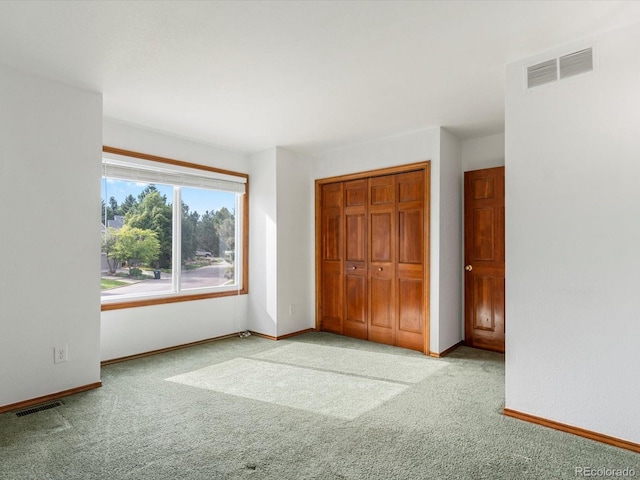 unfurnished bedroom featuring light carpet and a closet