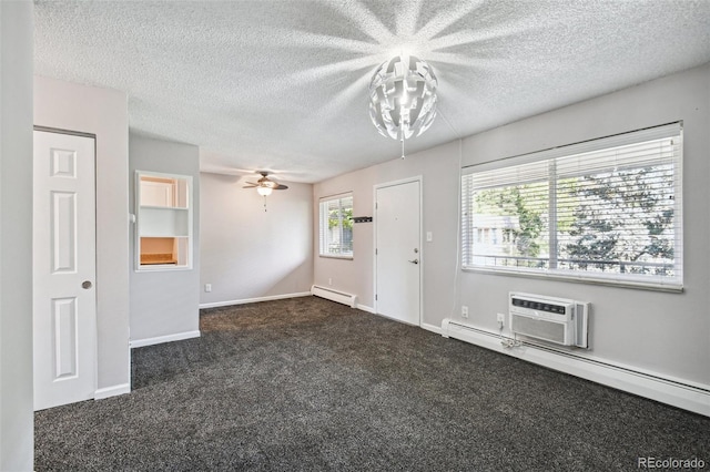 interior space with baseboard heating, an AC wall unit, a textured ceiling, and dark colored carpet