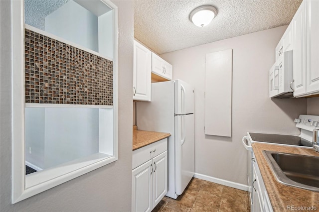 kitchen with white cabinets, a textured ceiling, white appliances, and a sink