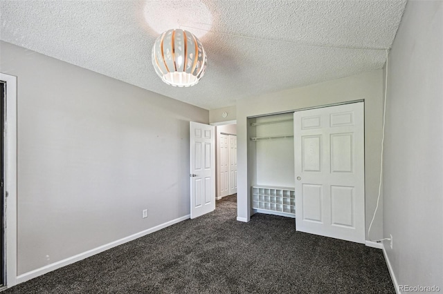 unfurnished bedroom with a textured ceiling, dark colored carpet, and a closet