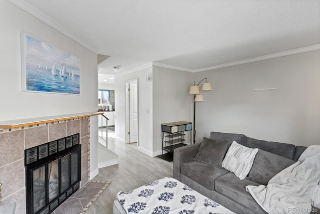 living room with ornamental molding, a tile fireplace, a textured ceiling, and hardwood / wood-style floors