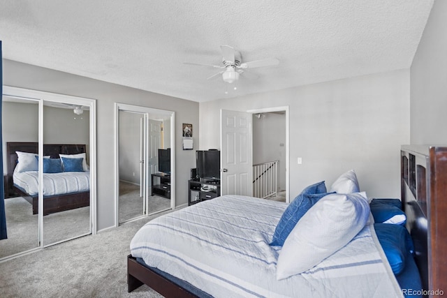 bedroom with ceiling fan, two closets, carpet, and a textured ceiling