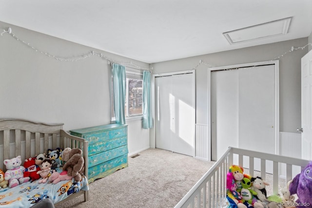 carpeted bedroom with a crib and multiple closets