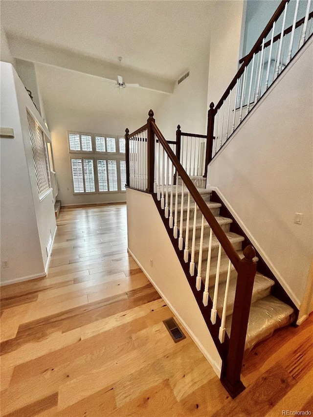 stairs featuring hardwood / wood-style flooring and ceiling fan