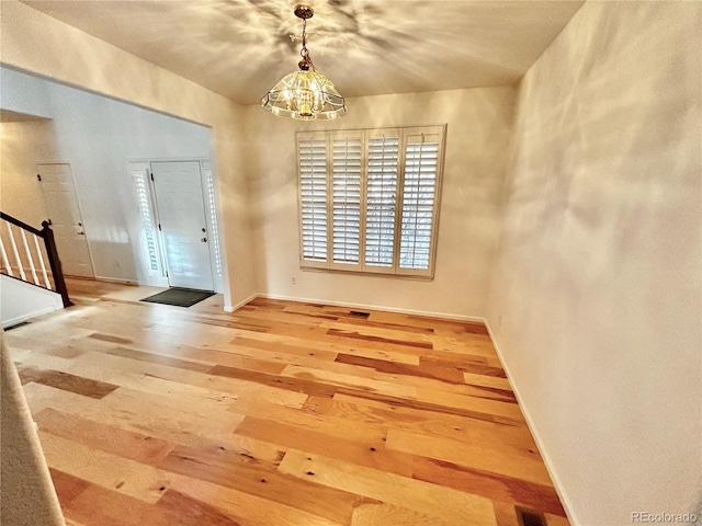 entrance foyer with wood-type flooring and an inviting chandelier