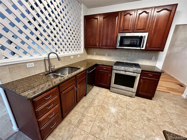 kitchen with sink, appliances with stainless steel finishes, light tile patterned flooring, decorative backsplash, and dark stone counters