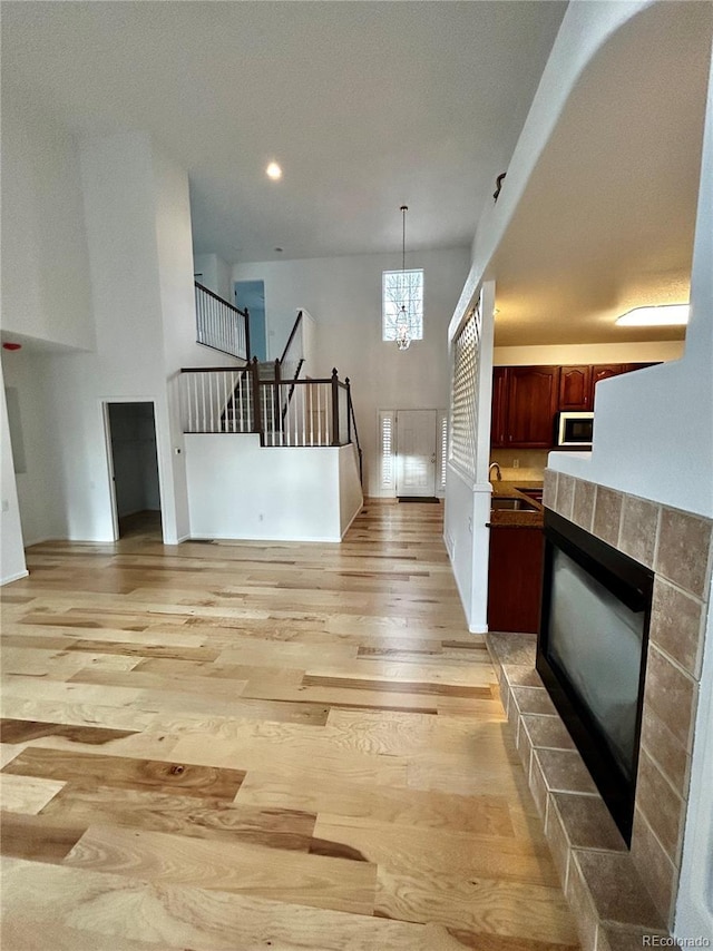 interior space with a high ceiling, an inviting chandelier, a fireplace, and light hardwood / wood-style floors