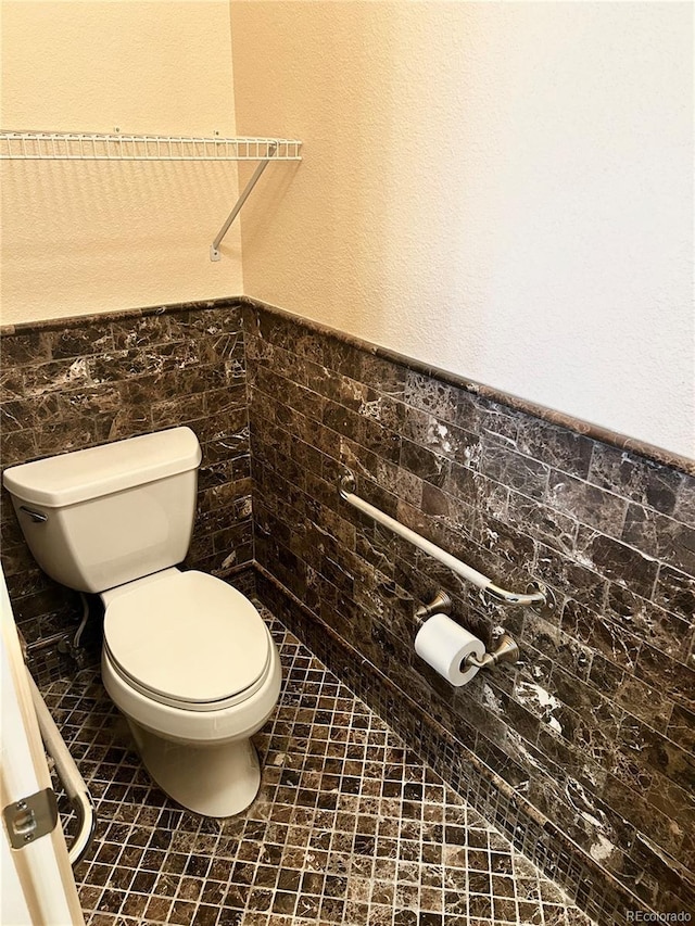 bathroom featuring tile patterned flooring, tile walls, and toilet