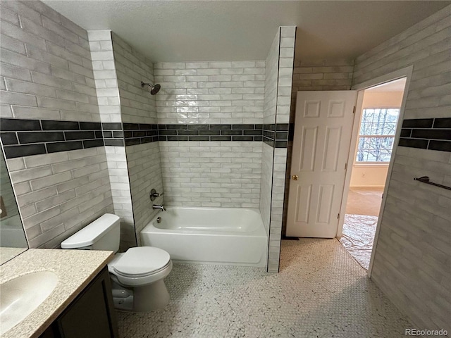 full bathroom featuring vanity, tiled shower / bath, and toilet