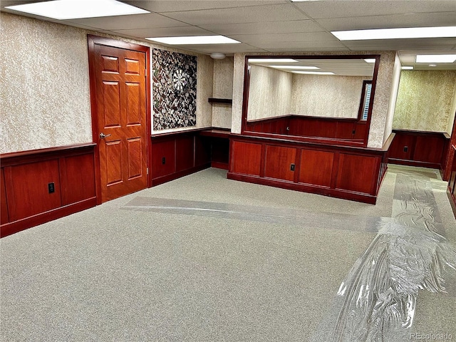 interior space with a paneled ceiling and light carpet