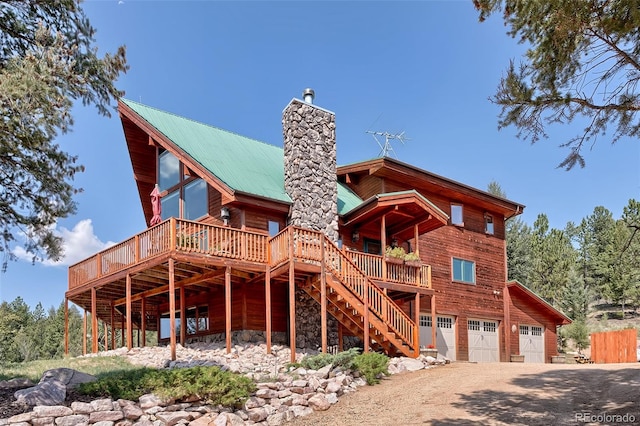 rear view of house featuring a wooden deck and a garage