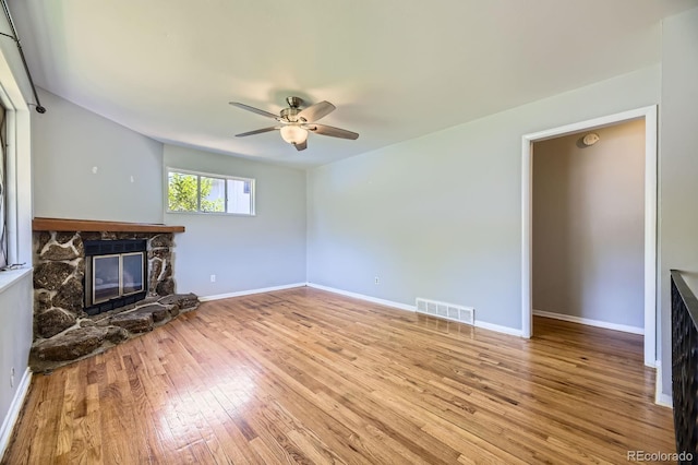 1750 S Dale Ct, Denver, CO 80219 - unfurnished living room featuring a stone fireplace, a ceiling fan, and wood-type flooring