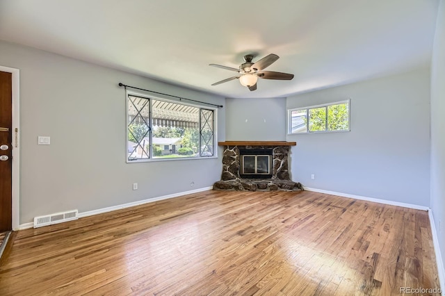 1750 S Dale Ct, Denver, CO 80219 - unfurnished living room with ceiling fan, a stone fireplace, and wood finished floors