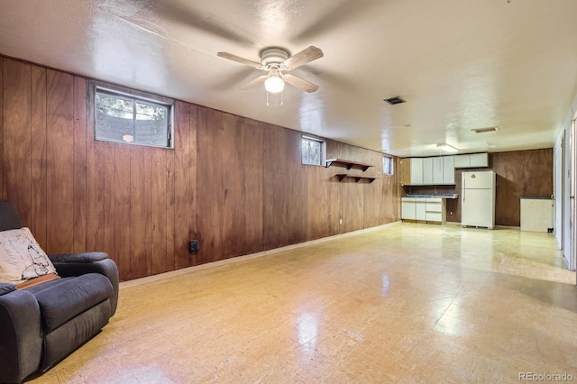 1750 S Dale Ct, Denver, CO 80219 - living room with wood walls, ceiling fan, and light floors