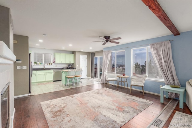 unfurnished living room with baseboards, hardwood / wood-style floors, beam ceiling, a sink, and recessed lighting