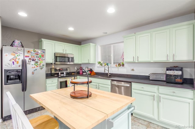 kitchen with dark countertops, appliances with stainless steel finishes, a sink, and recessed lighting