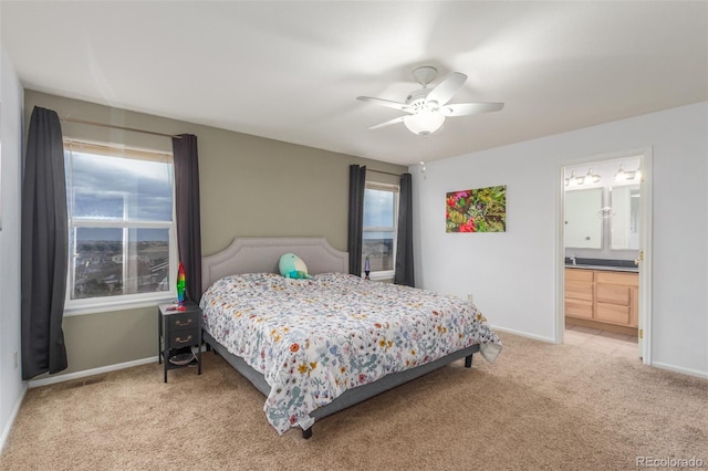 bedroom with light carpet, ceiling fan, baseboards, and ensuite bathroom