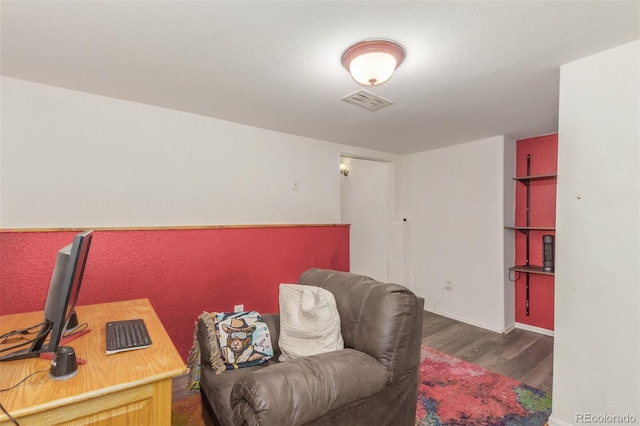 living area with wood finished floors, visible vents, and baseboards