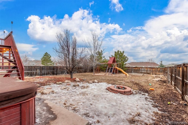 view of yard featuring a playground, a hot tub, stairway, a fenced backyard, and a fire pit