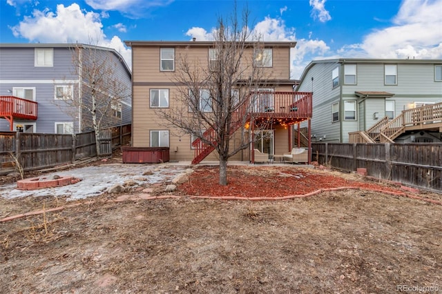 rear view of property with a hot tub, a patio area, a fenced backyard, and a deck