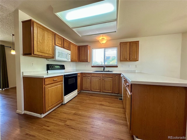 13191 Umatilla St, Denver, CO 80234 - kitchen with range with electric stovetop, white microwave, a peninsula, dark wood-style flooring, and brown cabinets