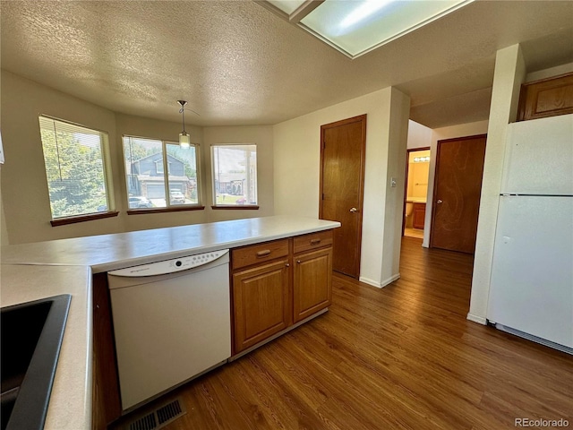 13191 Umatilla St, Denver, CO 80234 - kitchen with white appliances, dark wood-style flooring, light countertops, brown cabinetry, and a textured ceiling