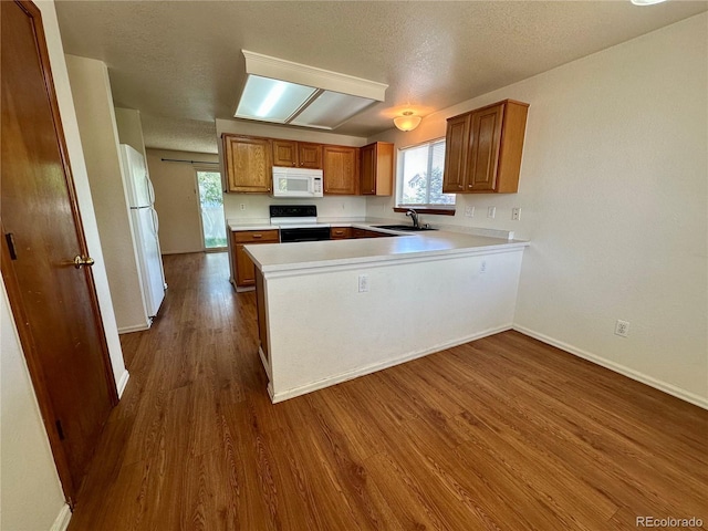 13191 Umatilla St, Denver, CO 80234 - kitchen featuring white appliances, brown cabinets, dark wood-type flooring, a peninsula, and light countertops