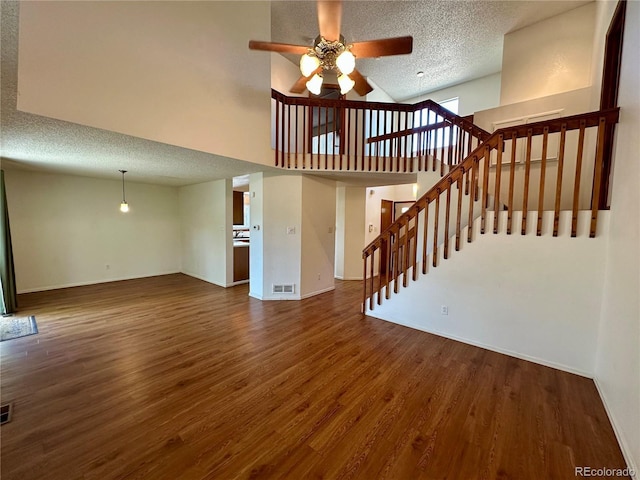 13191 Umatilla St, Denver, CO 80234 - unfurnished living room featuring ceiling fan, a textured ceiling, wood finished floors, a high ceiling, and stairway