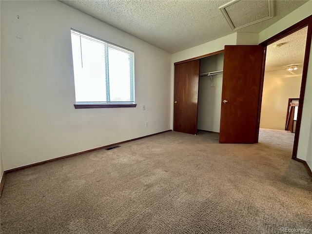 13191 Umatilla St, Denver, CO 80234 - unfurnished bedroom featuring light colored carpet, a closet, a textured ceiling, and attic access