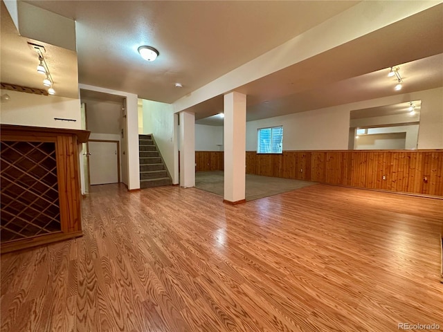 13191 Umatilla St, Denver, CO 80234 - unfurnished living room featuring light wood-type flooring, wainscoting, stairway, and wooden walls