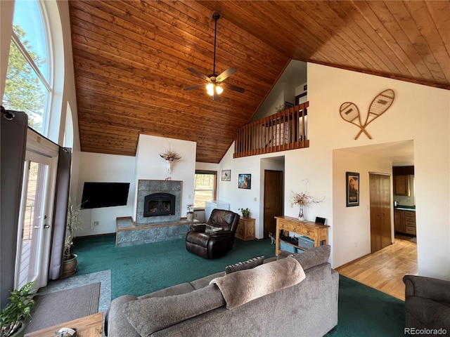 carpeted living room featuring wooden ceiling, high vaulted ceiling, a fireplace, and ceiling fan