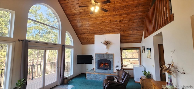 carpeted living area with wood ceiling, a high ceiling, a tile fireplace, and a ceiling fan