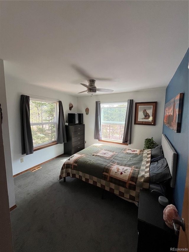 carpeted bedroom featuring multiple windows, visible vents, baseboards, and a ceiling fan