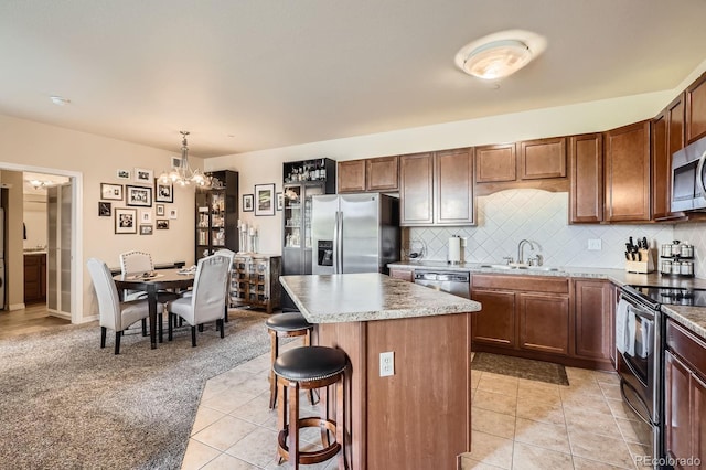 7292 S Blackhawk St Unit 2-204, Englewood, CO 80112 - kitchen featuring appliances with stainless steel finishes, a sink, a chandelier, a kitchen bar, and a center island