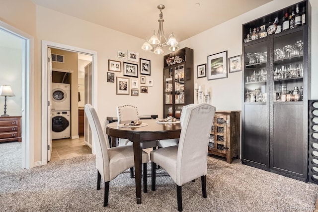 7292 S Blackhawk St Unit 2-204, Englewood, CO 80112 - dining room with stacked washer and clothes dryer, carpet flooring, a chandelier, and a baseboard heating unit