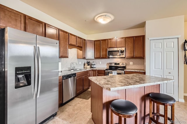 7292 S Blackhawk St Unit 2-204, Englewood, CO 80112 - kitchen with appliances with stainless steel finishes, a sink, a kitchen bar, decorative backsplash, and light tile patterned flooring