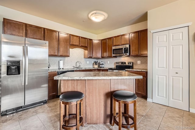 7292 S Blackhawk St Unit 2-204, Englewood, CO 80112 - kitchen featuring appliances with stainless steel finishes, a breakfast bar, a kitchen island, and backsplash