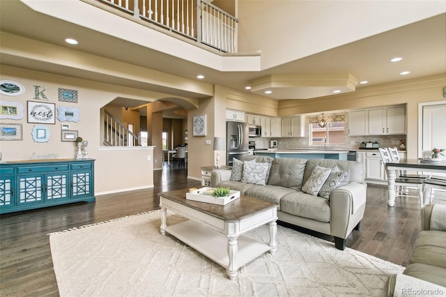 living area featuring arched walkways, dark wood-style flooring, baseboards, and recessed lighting
