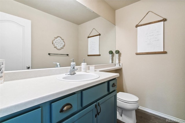 half bath featuring toilet, vanity, wood finished floors, and baseboards