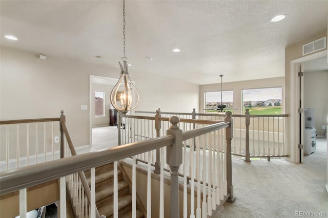 corridor featuring an upstairs landing, light carpet, recessed lighting, and a chandelier