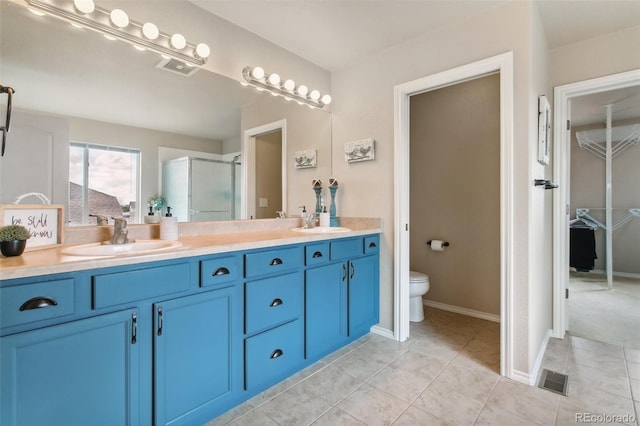 bathroom with a stall shower, double vanity, tile patterned flooring, toilet, and baseboards