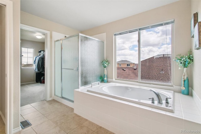 full bath featuring a stall shower, a spacious closet, a bath, tile patterned flooring, and baseboards