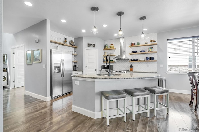 484 N Jamestown Way, Aurora, CO 80018 - kitchen with stainless steel fridge, open shelves, wall chimney exhaust hood, decorative backsplash, and light stone countertops