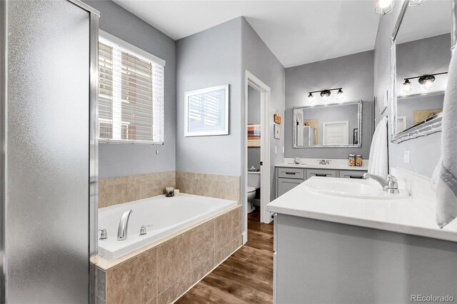 484 N Jamestown Way, Aurora, CO 80018 - bathroom featuring toilet, wood finished floors, a bath, double vanity, and a shower stall