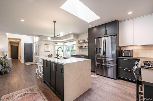 995 Chase St, Lakewood, CO 80214 - kitchen featuring appliances with stainless steel finishes, a skylight, wood finished floors, decorative backsplash, and recessed lighting